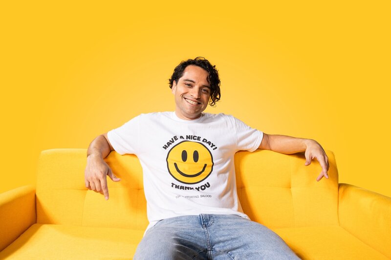a man smiling while wearing a smiley face t-shirt