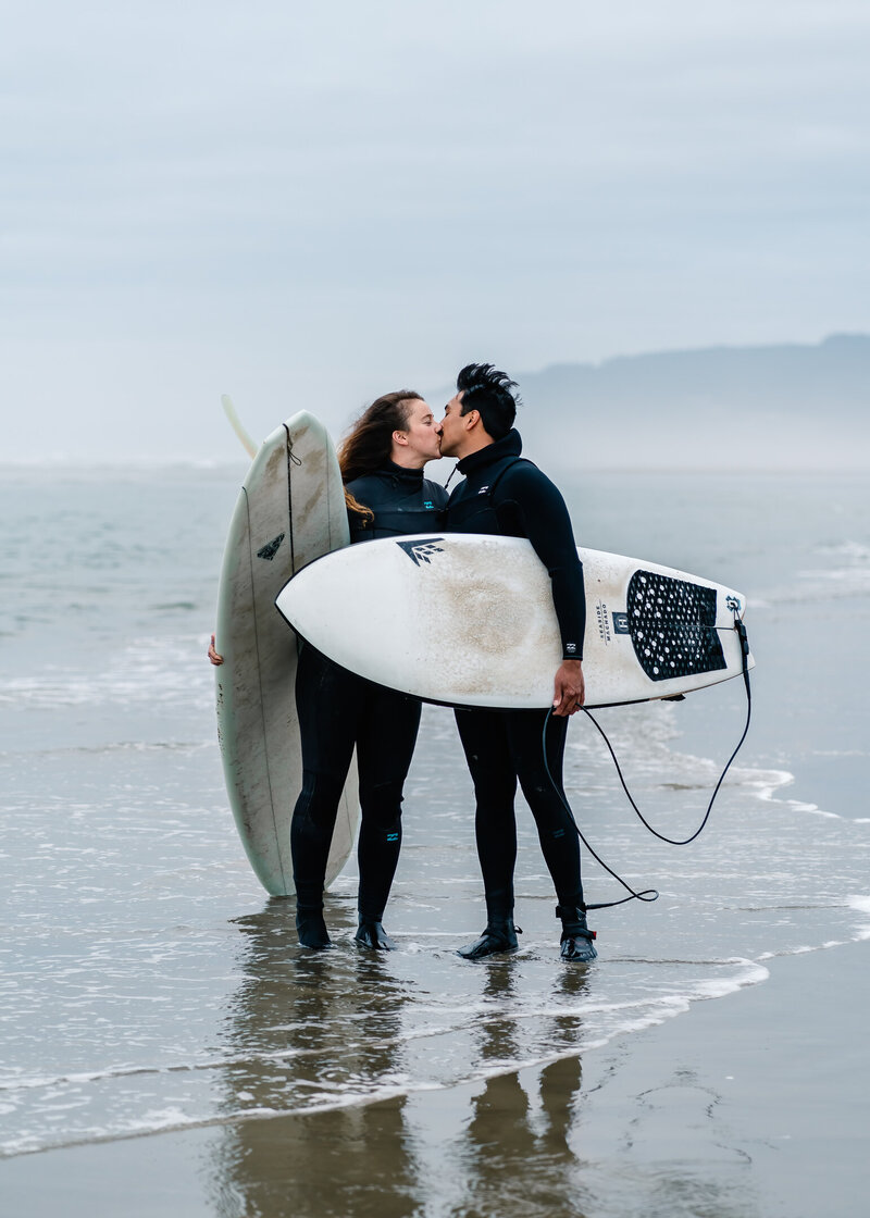 To celebrate their Oregon coast elopement, a couple kisses after surfing.