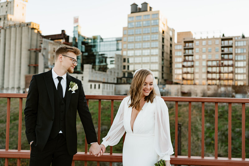 Megan and Logan posing for their wedding portraits downtown Minneapolis at Stone Arch bridge.