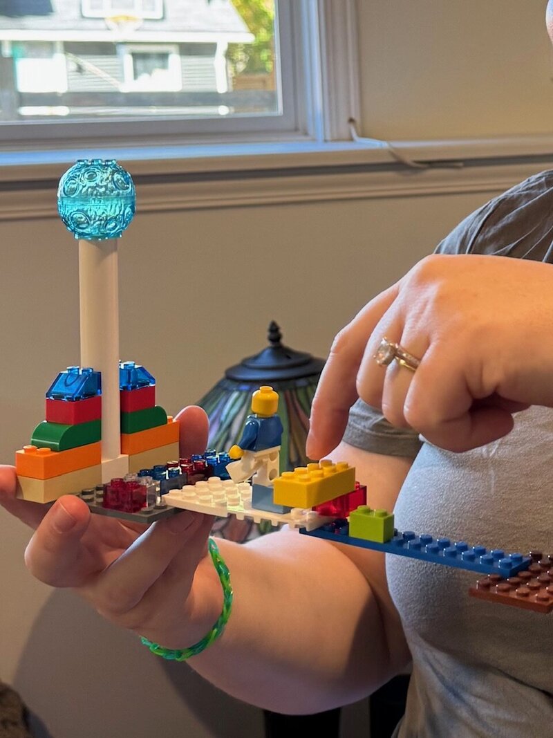 LEGO Serious Play model and participant pointing at the LEGO creation. 
