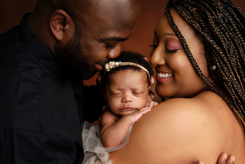 st-louis-family-photographer-mother-and-father-smiling-holding-newborn-in-middle