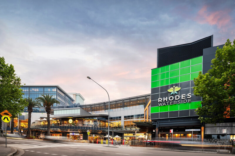 Exterior view of Rhodes Waterslide Shopping Centre with green signage and multi-level layout. Retail Upgrade project by Serlana Construction.
