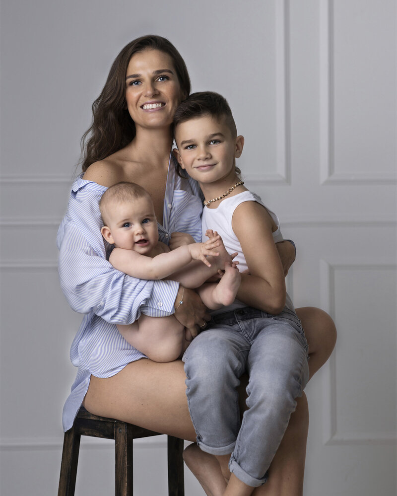 A family portrait of a smiling mother and  her children on a simple grey background