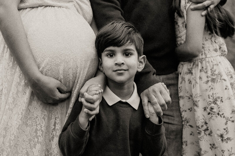 Young son holding hands with family in front of mom's pregnant belly