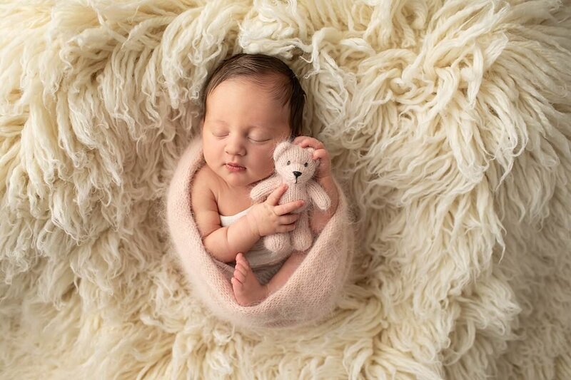 Baby boy holding teddy bear wrapped in a swaddle by Maryland Newborn Photographer