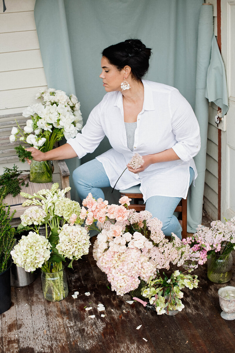 Jasmin Norwood arranging flowers on a farmhouse porch in Tivoli, NY