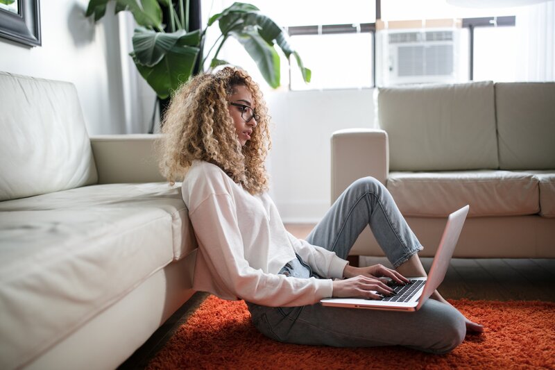 Biracial woman looking at laptop while sitting on floor