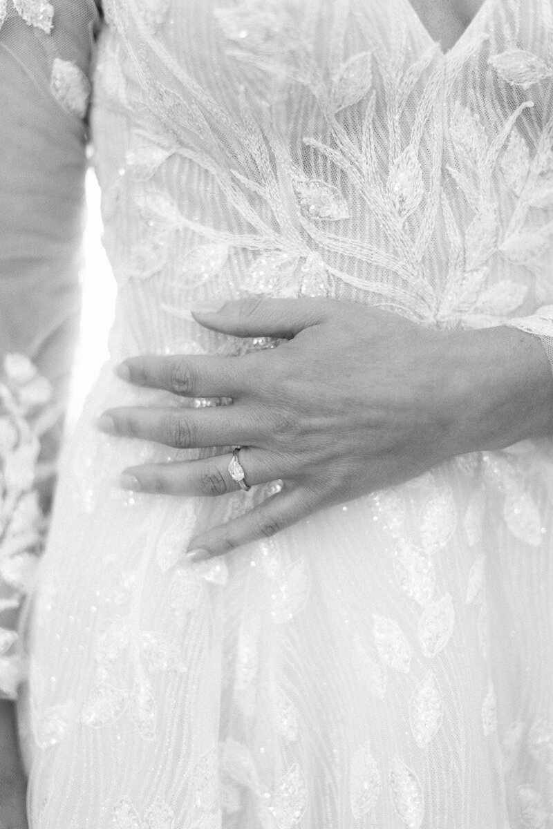Close up photo of brides had in her wedding dress showing off engagement ring