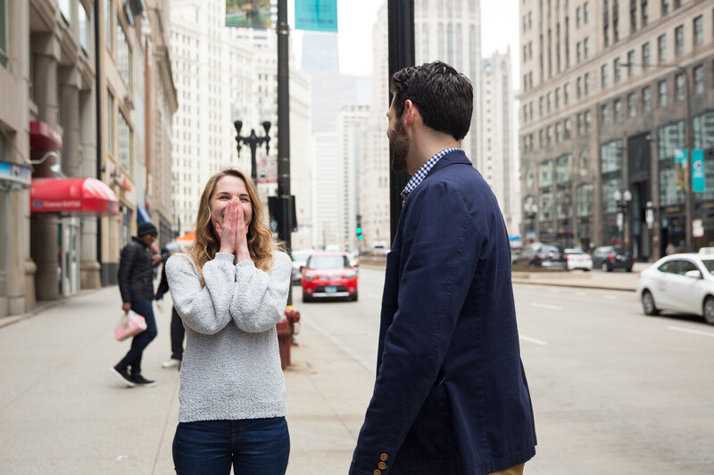 couple laughing after surprise proposal woman gasping from surprise engagement downtown chicago mag mile