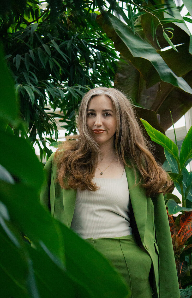 Content repurposing strategist standing in a greenhouse wearing a green suit.