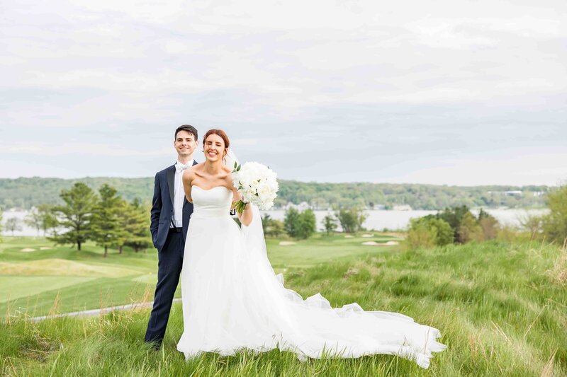 Happy bride pulling groom with white bouquet in Lake Geneva, Wisconsin.