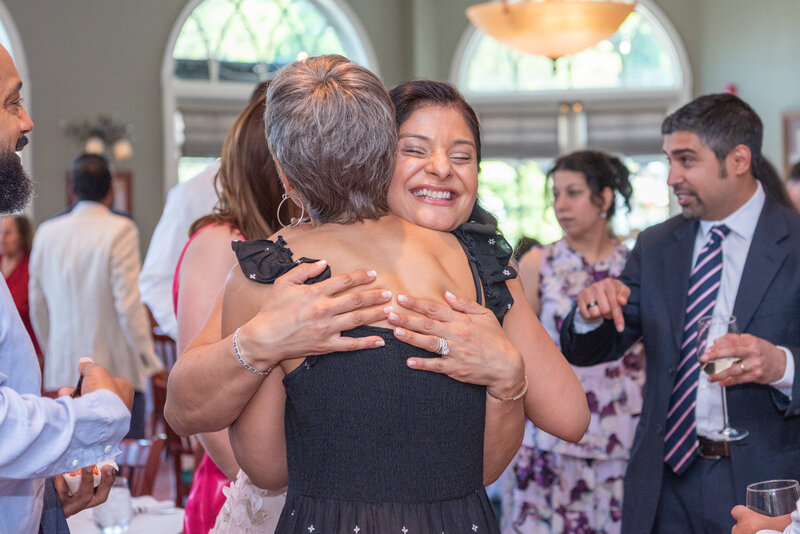 Two woman hugging at an event and smiling.