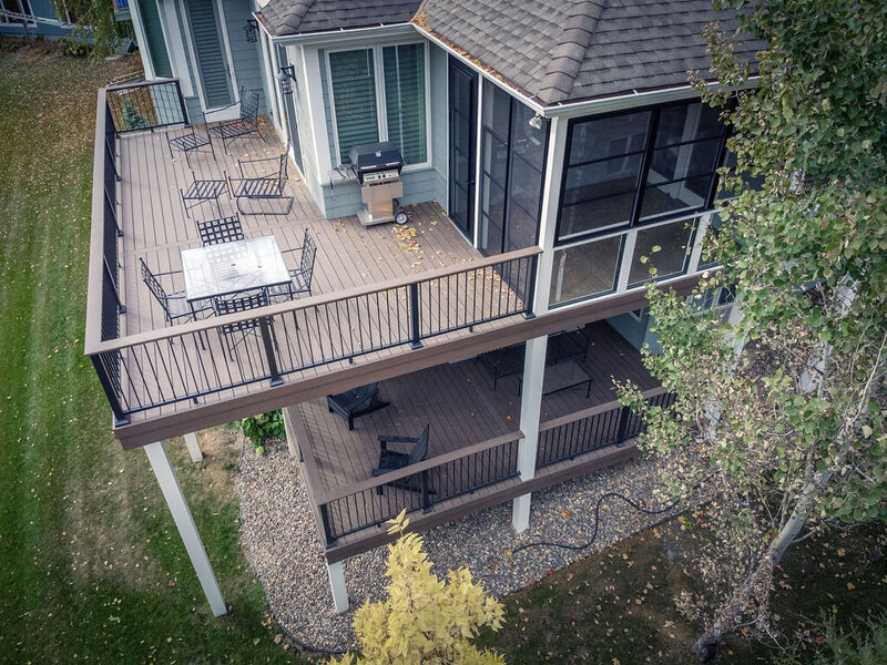 Aerial view of a two-level composite deck where the upper deck is larger and has a 3-season porch attached, and the lower deck is smaller and there are no stairs between the two levels. 