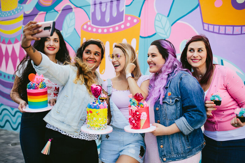 Bakery staff taking a selfie in front of a bright colorful mural in Albany New York