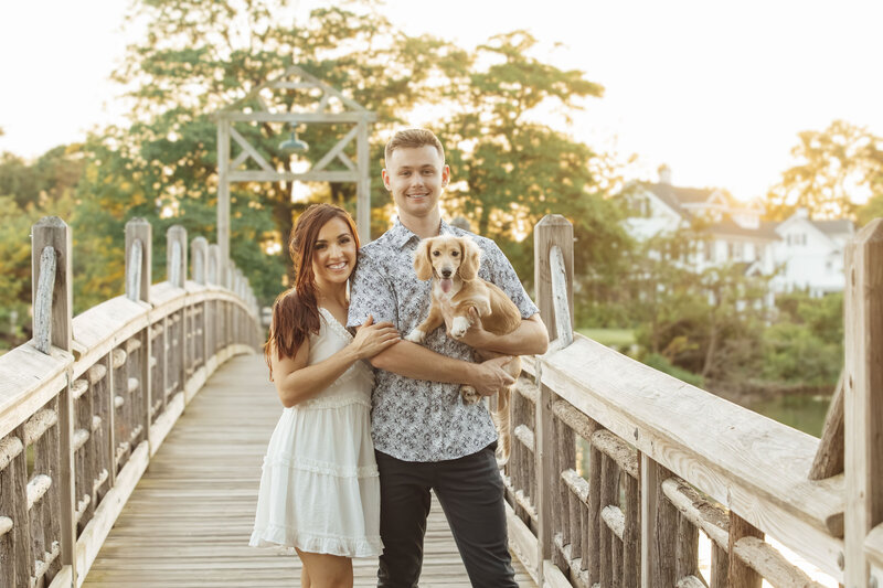 Spring Lake Engagement Session | Couple Holding Their Dog at Sunset on Bridge | Spring Lake, New Jersey