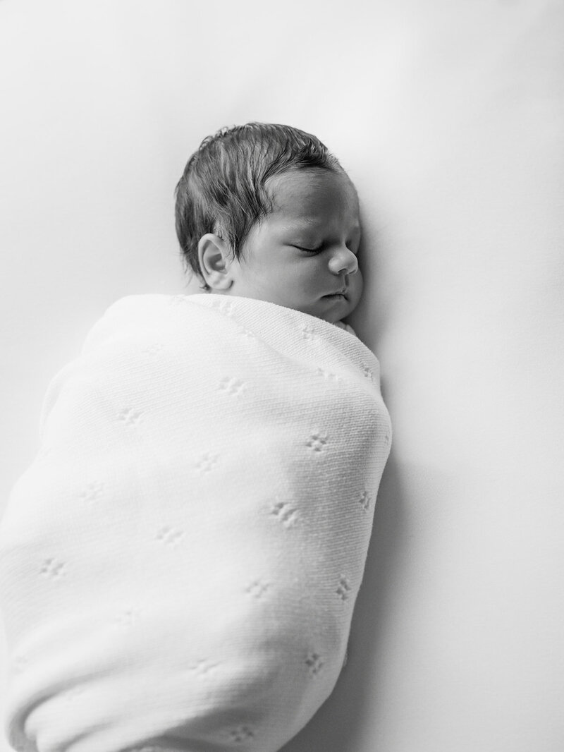 A newborn sleeping while wrapped in a blanket during a Richmond newborn photographer session by Katie Stansfield Photography.