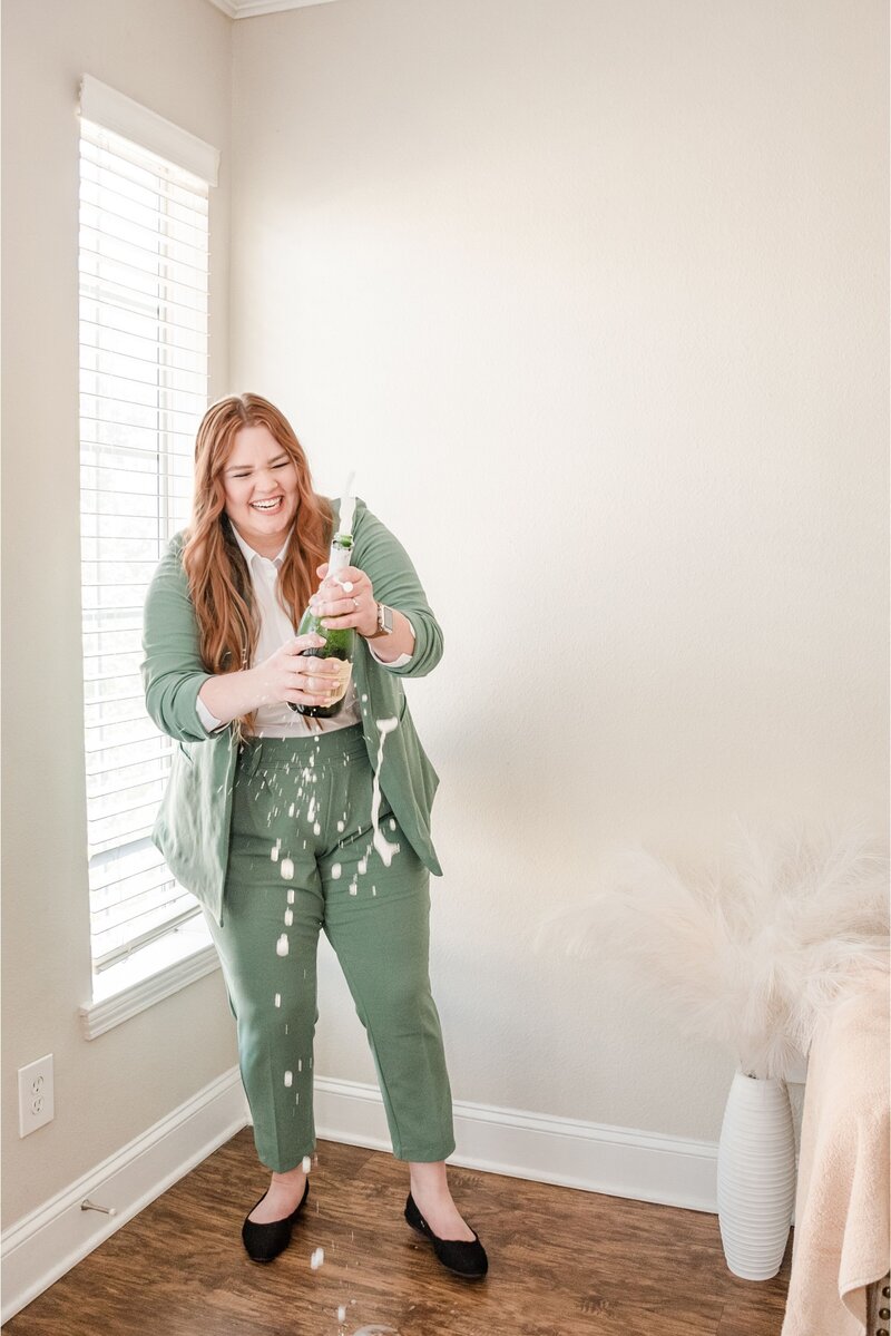 Elyse Stokes, creative owner of E Stokes Creations, popping a bottle of champagne to celebrate a successful collaboration