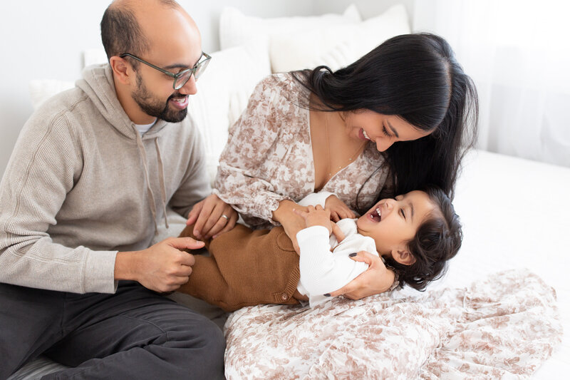 Parents playing with their son on the bed