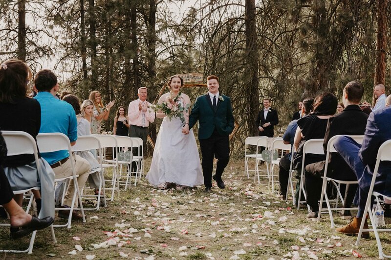 A joyful moment as the bride and groom walk down the aisle as newlyweds, surrounded by love and celebration. Captured in Spokane by Blair Voss, specializing in cinematic wedding photography.