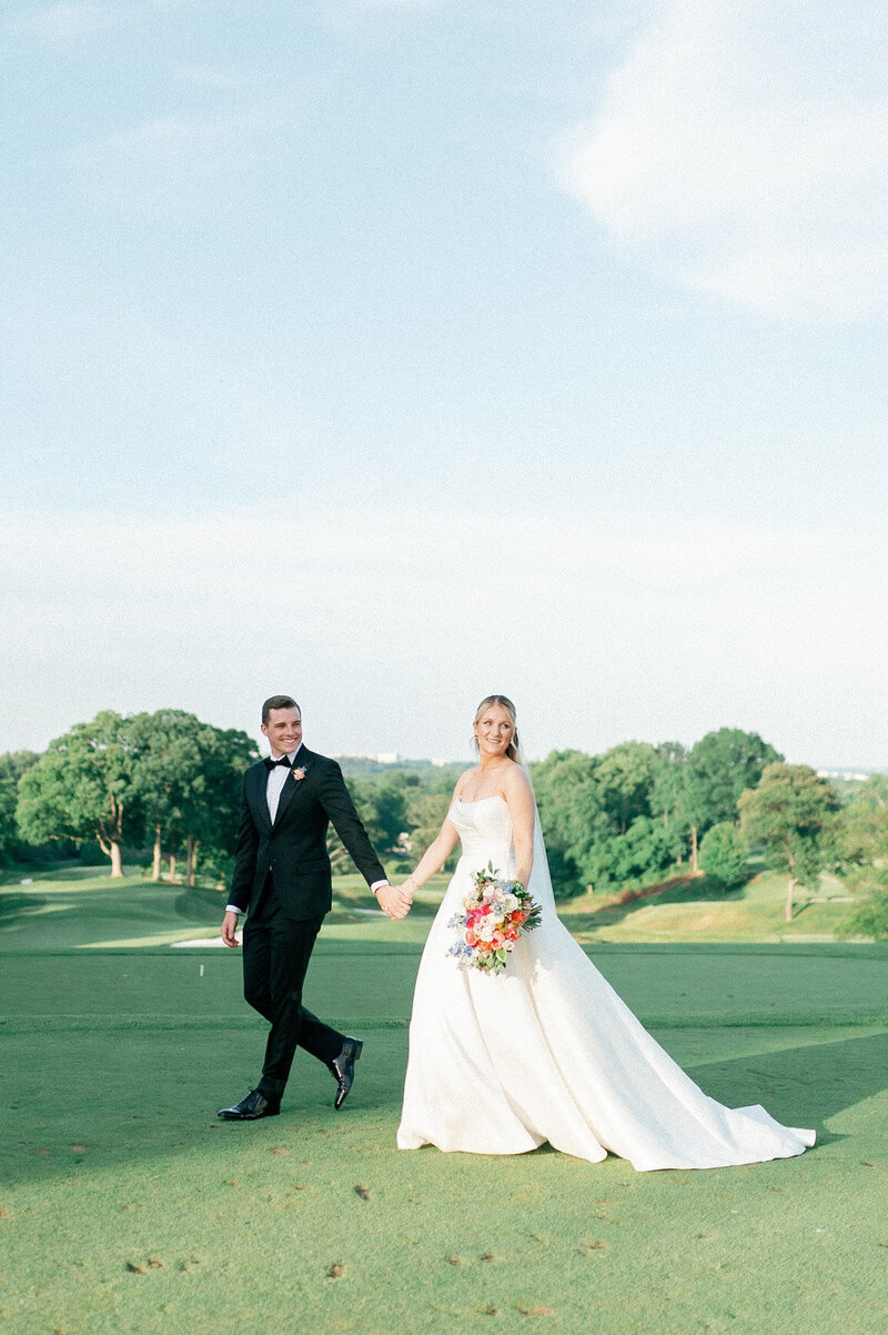 a bride and groom walking on a golf course