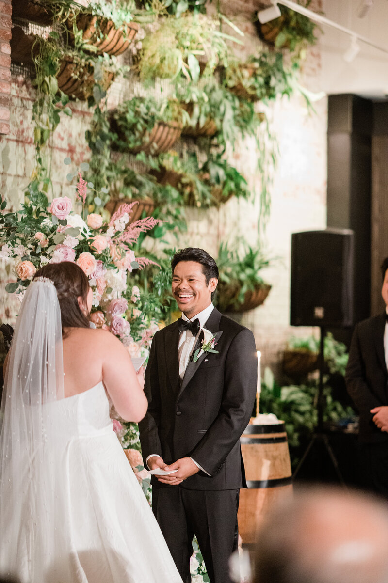 Groom smiles widely at his bride before the exchanging of vows