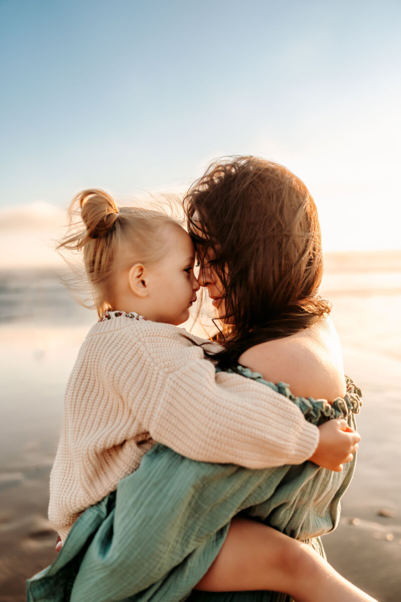 Family Photographer, a mother holds her daughter at the beach