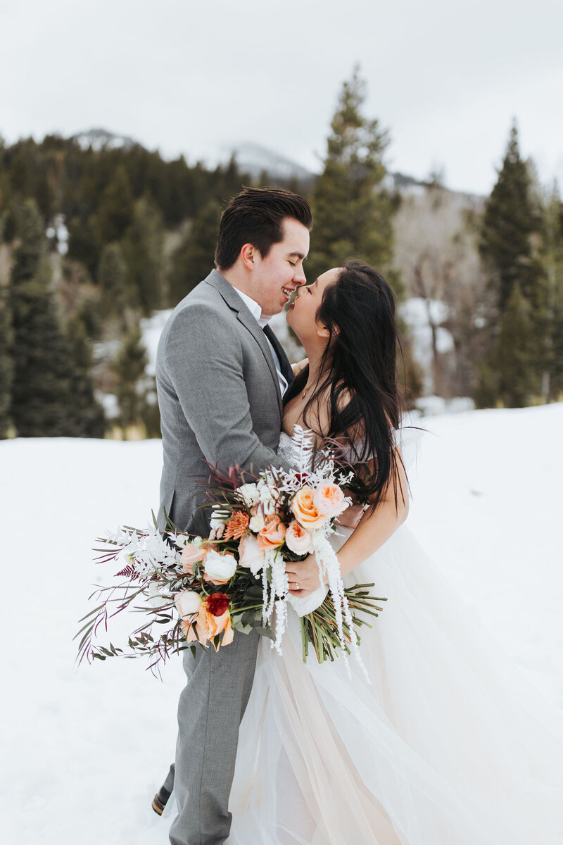 bride wedding couple kissing in the mountains in the snow