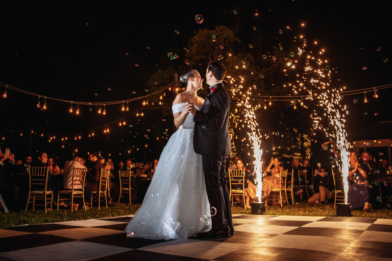 Shannon Lee, an Orlando wedding photographer capturing a magical first dance under sparkling fireworks and twinkling lights, surrounded by guests enjoying the celebration.