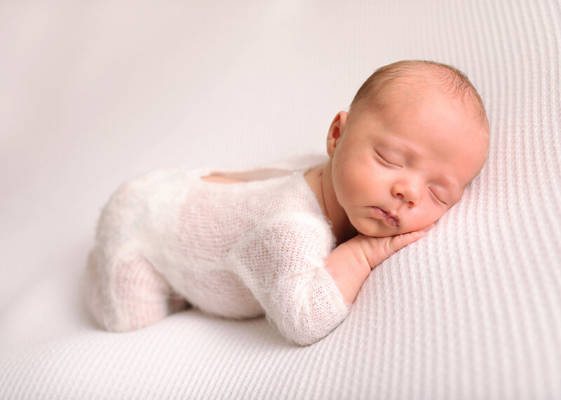 Chin on hand newborn in white