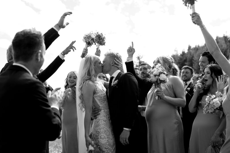 Picture of bride and groom kissing and bridal party celebrating during their montana wedding