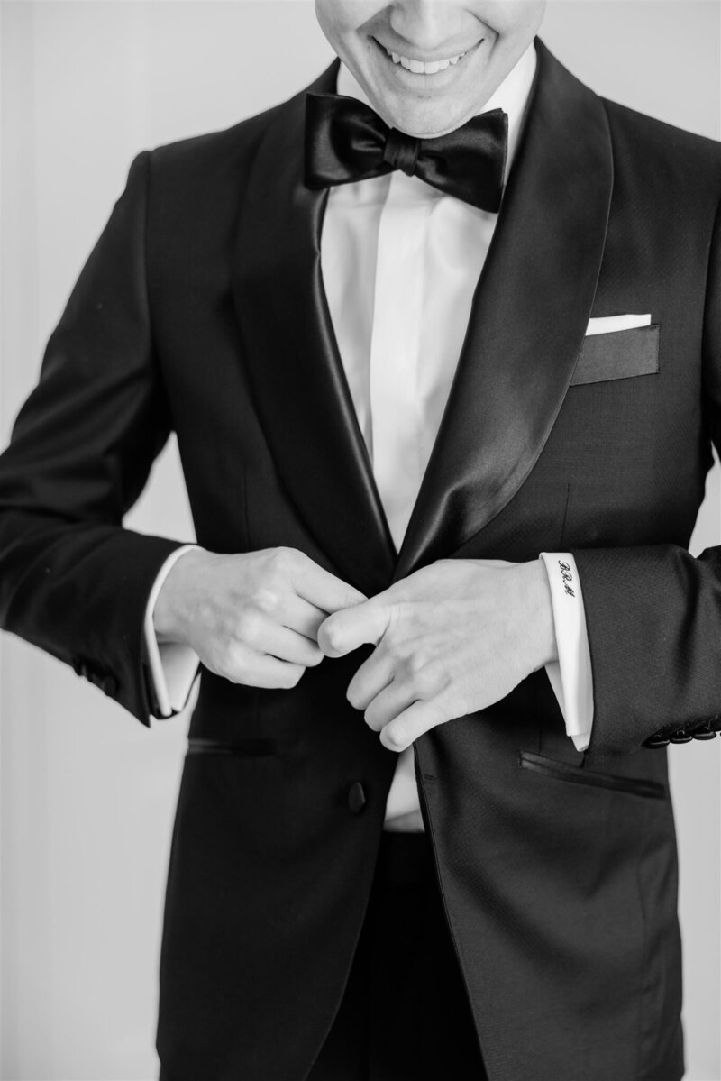 A black and white closeup of the groom buttoning his tux at the Alfond Inn in Winter Park. 