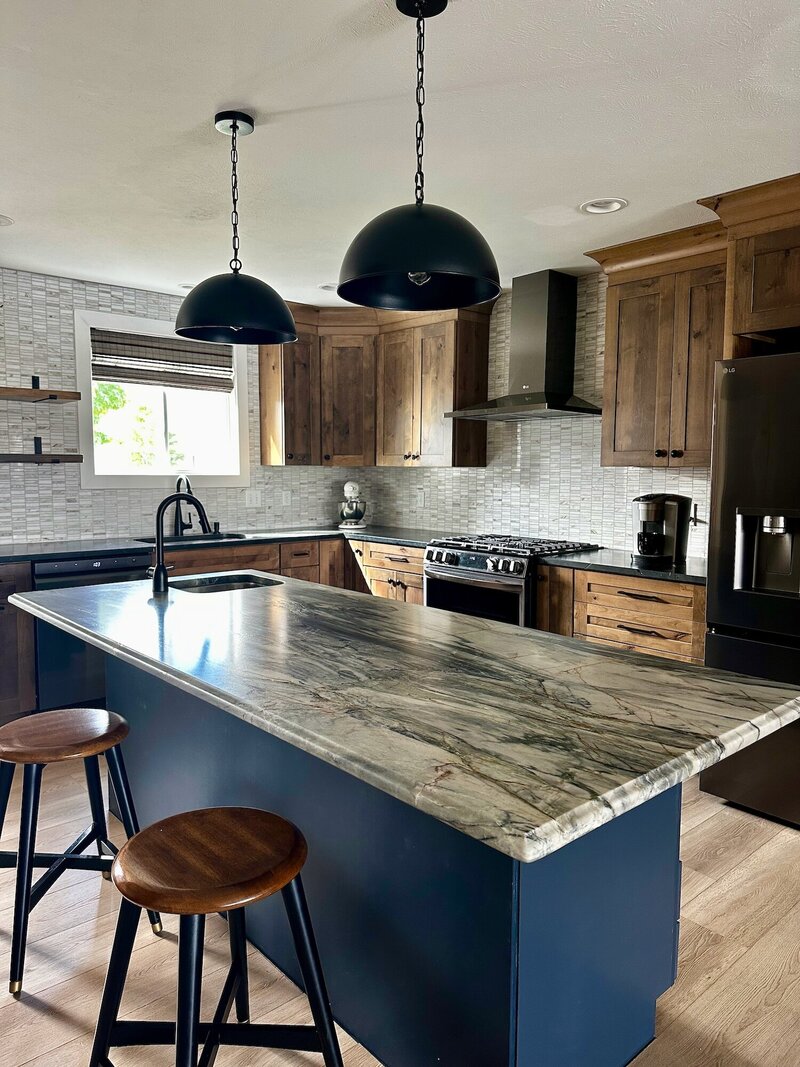 Modern kitchen complete with marble countertops, wood and blue painted cabinets.