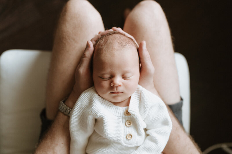A Brisbane father cradles his baby girl's head in his hands showing just tiny she is.