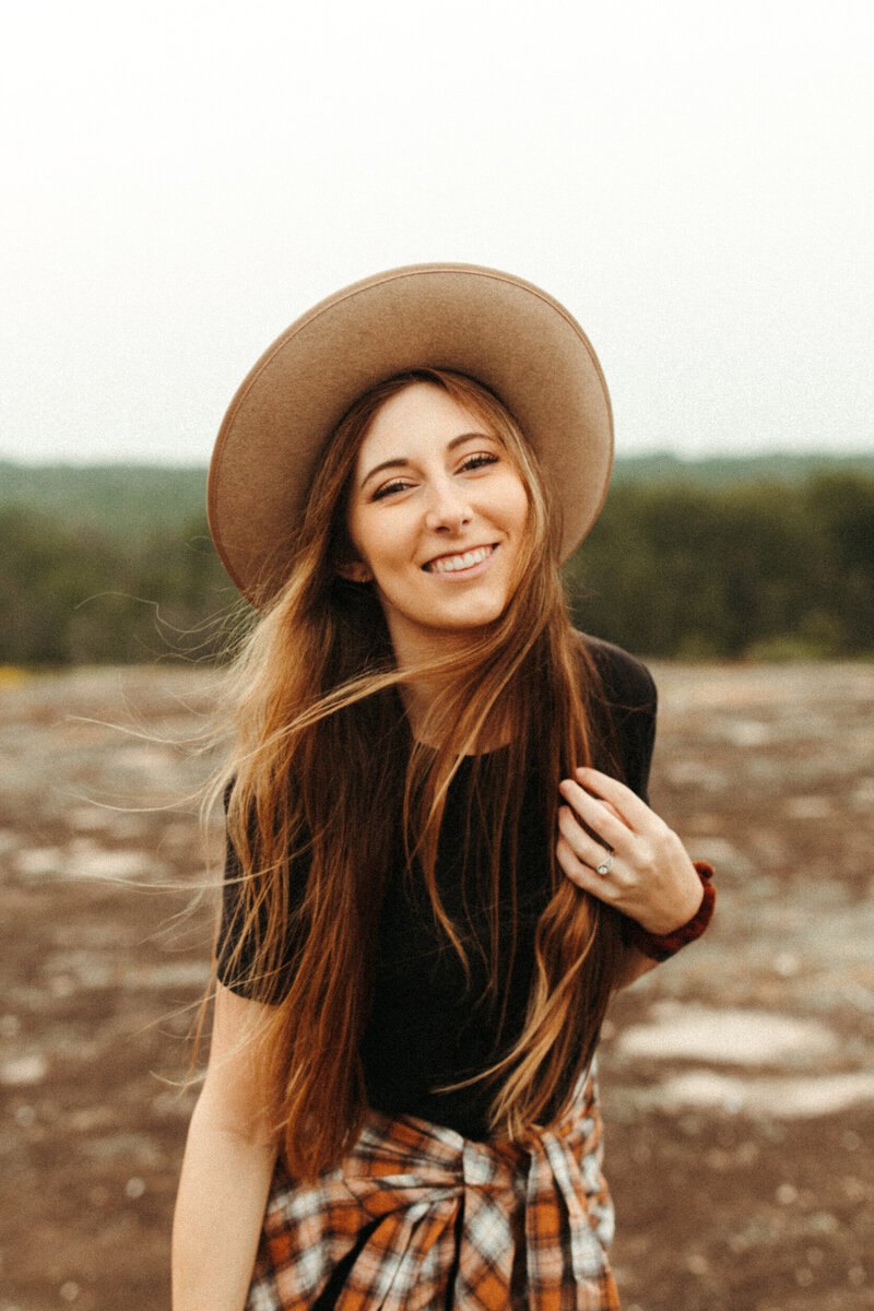 Photographer in hat smiling and posing on mountain top