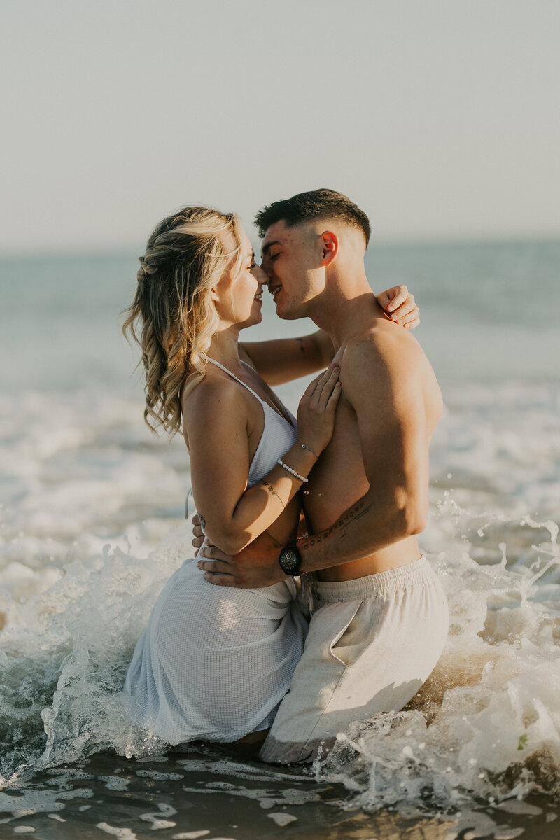 Couple enlacé dans les vagues de l'océan lors d'une séance photo couple en Vendée.