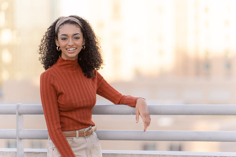 high school girl leaning on the railing of a parking garage during senior photos in Fairfax County, Virginia