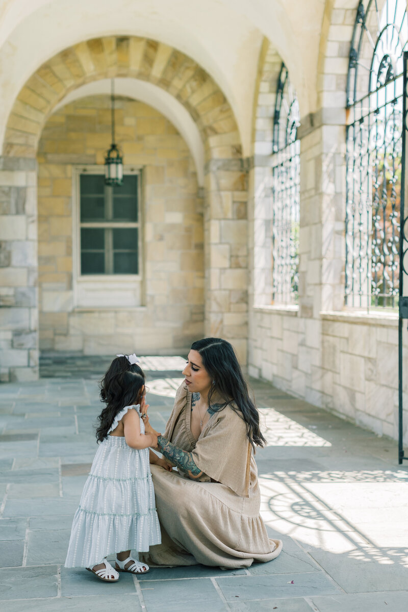 A mom wearing a flowy tan dress and a child wearing a blue sundress embrace in North Carolina