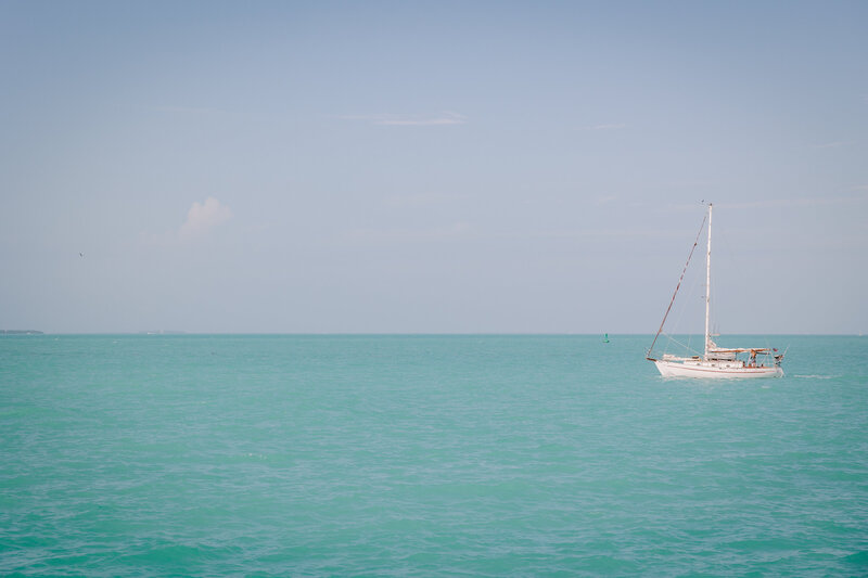 man and woman kissing while standing in front of the ocean