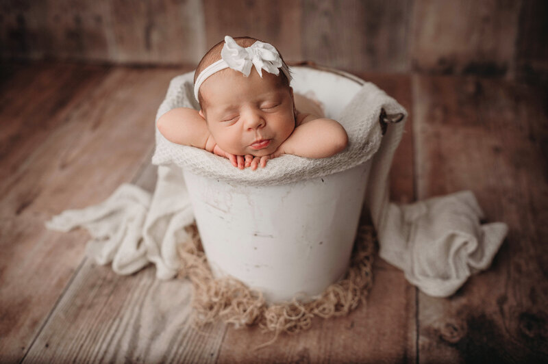 Stamford Newborn photographer Drea S Photocaptures newborn baby girl sleeping inside of a white bucket at beautiful Ct studio