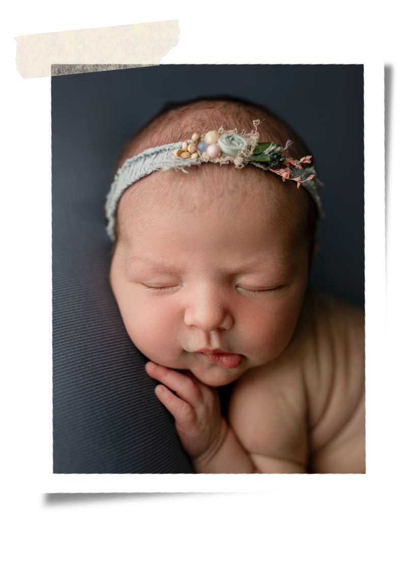 A newborn baby girl posed on a blue blanket.