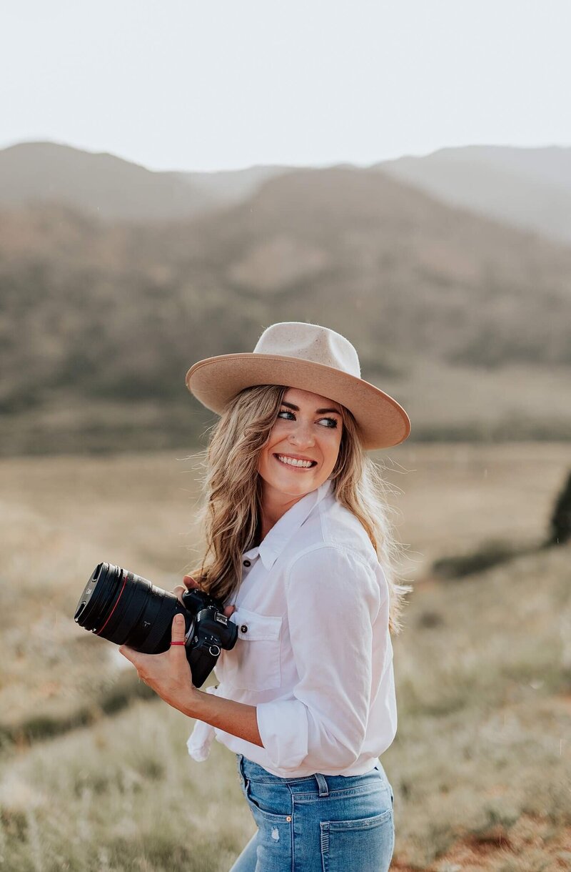 Michelle Betz Photography headshot of her smiling to the side, holding a camera. Captured in Colorado Springs, CO.