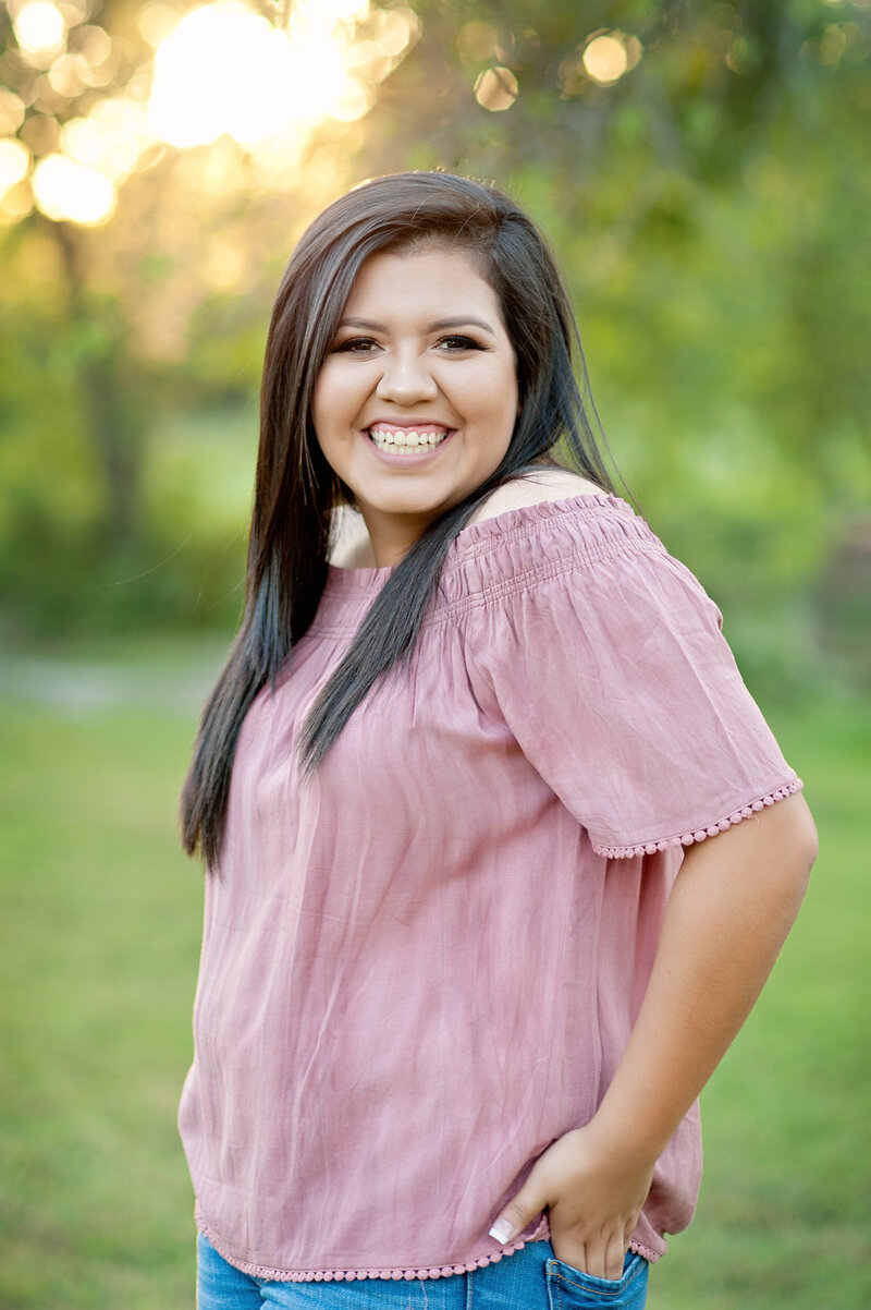 high school senior girl with long brown hair posing and smiling in winter garden, fl for her senior pictures with Melissa Vinsik