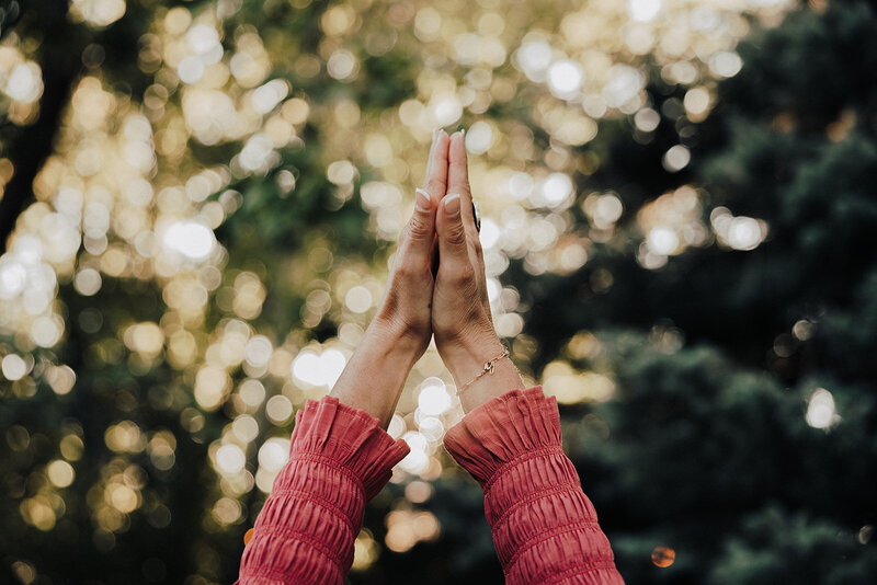 woman with her hands in prayer outstretched to the sky