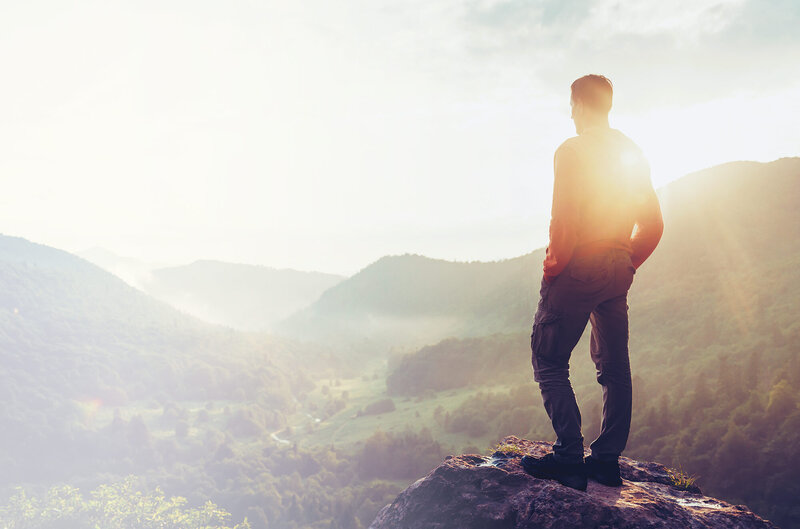 Person standing on a mountain at sunset