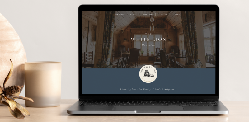 Laptop on desk showing website design and branding of The White Lion