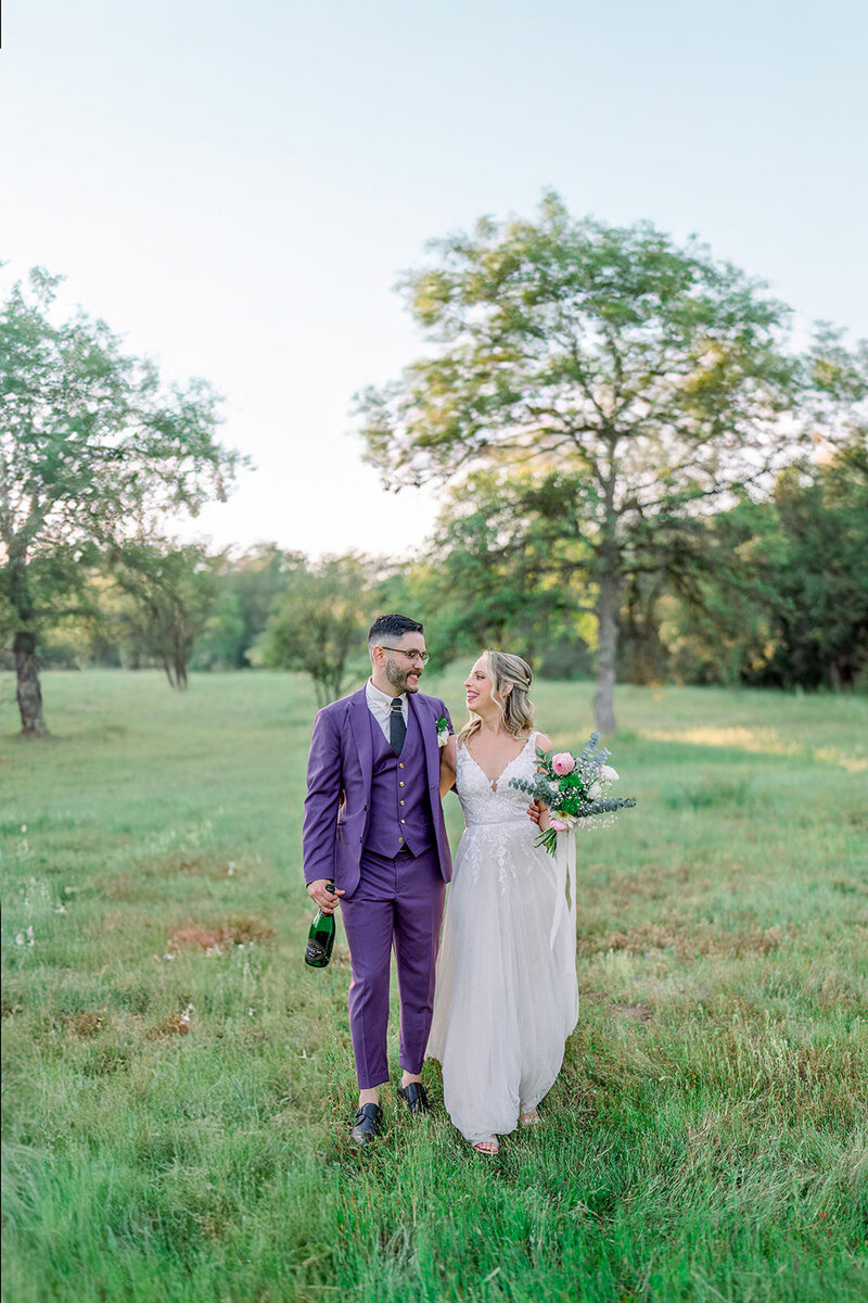 Tiffany Longeway Photography captures a blissful moment of a couple walking hand-in-hand through the sprawling fields of B.R. Cohn Winery in Sonoma. Dressed in a striking purple suit and a delicate bridal gown, this image reflects the unique and intimate atmosphere of a luxury vineyard wedding, perfect for couples who dream of a stylish and serene celebration in the heart of Sonoma’s wine country.