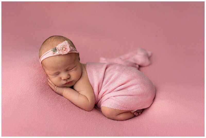 newborn baby girl with a pink blanket and pink background