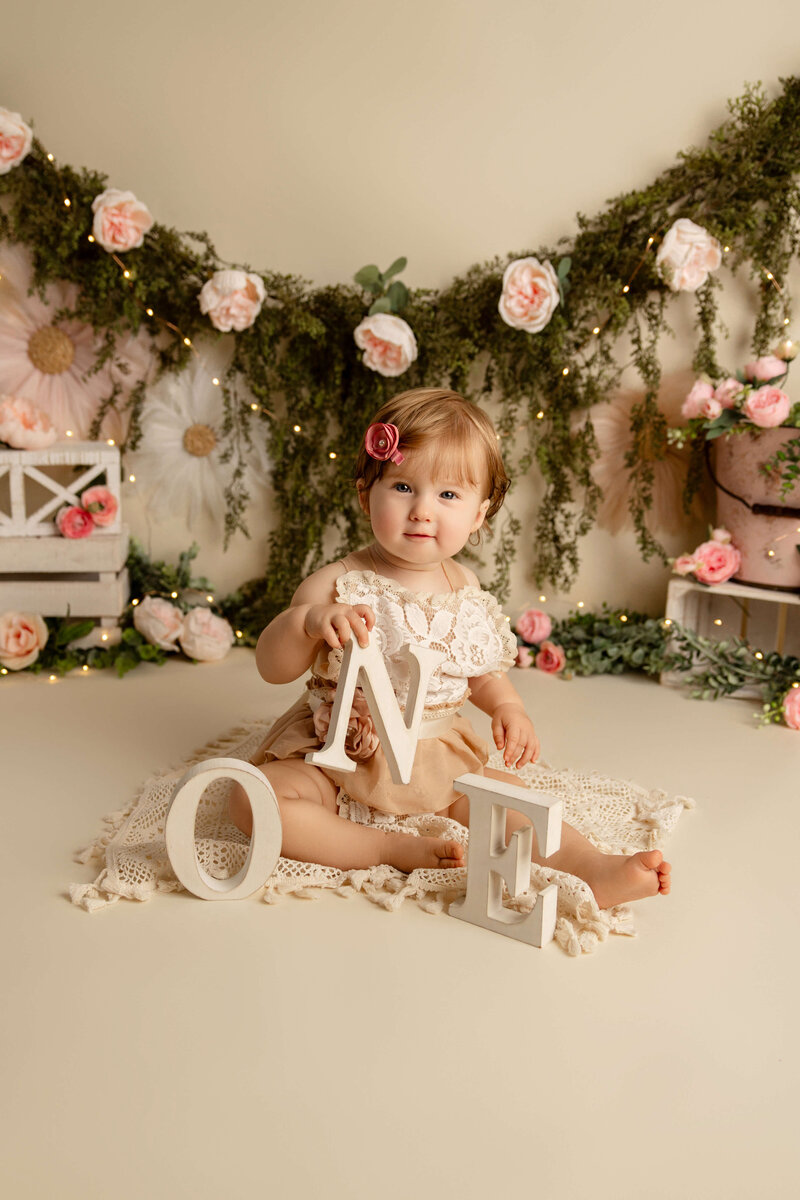 Newborn baby boy in a blue swaddle in a tan basket on a tan background
