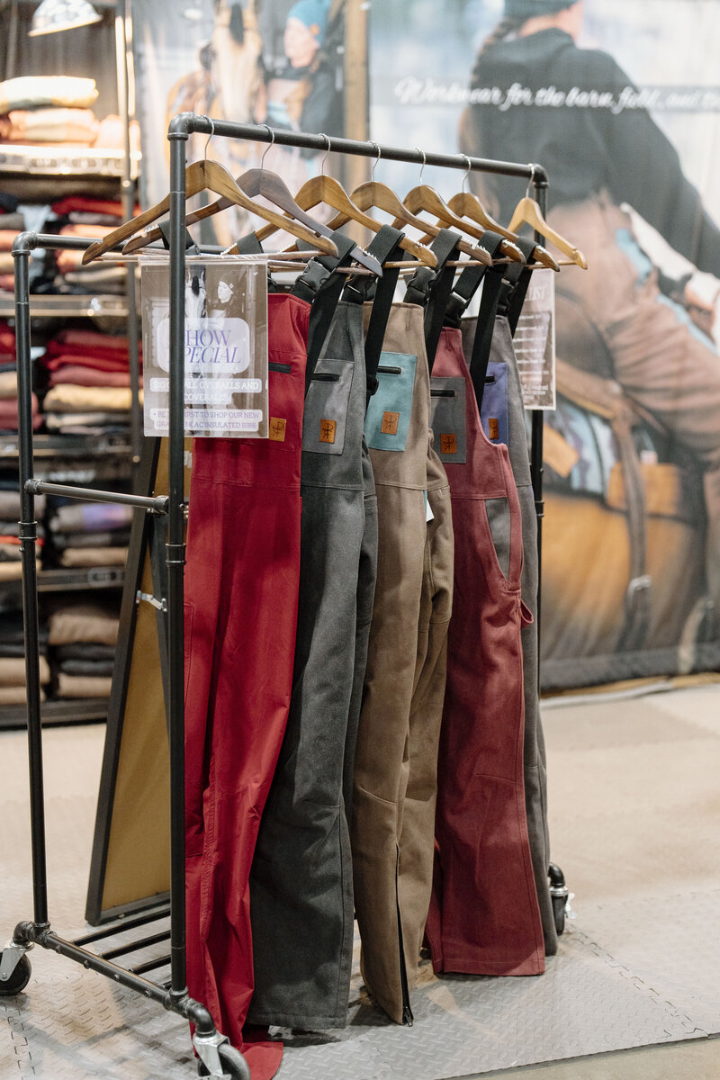 Woman's coveralls hanging on a rack at an agricultural trade show captured by a brand photographer