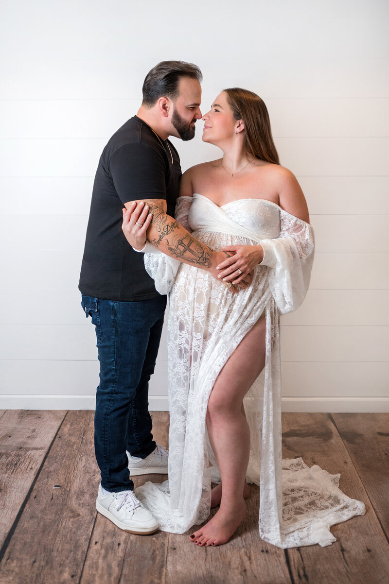 Couple holding pregnant belly durinng studio maternity session.